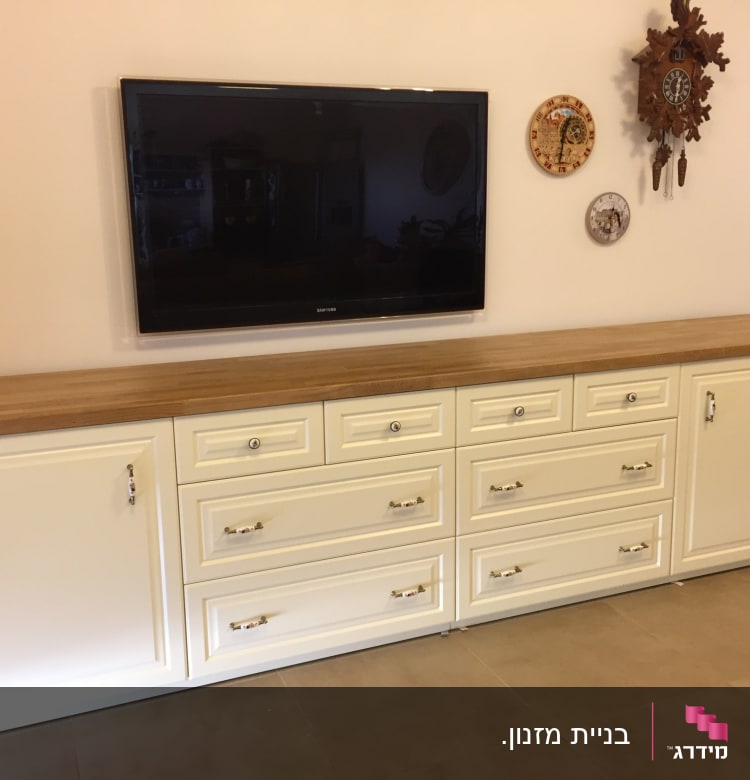 ארון מטבח עם משטח עץ וטלוויזיה תלויה על הקיר